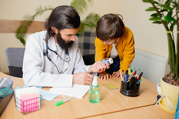 Image showing Paediatrician doctor examining a child in comfortabe medical office