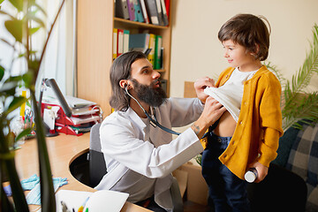 Image showing Paediatrician doctor examining a child in comfortabe medical office