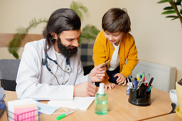 Image showing Paediatrician doctor examining a child in comfortabe medical office
