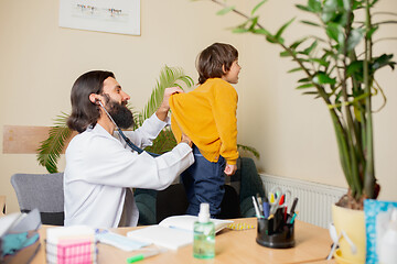 Image showing Paediatrician doctor examining a child in comfortabe medical office