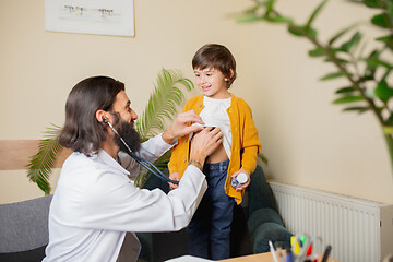 Image showing Paediatrician doctor examining a child in comfortabe medical office