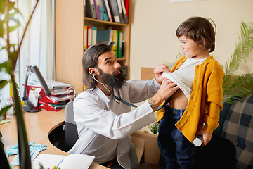 Image showing Paediatrician doctor examining a child in comfortabe medical office