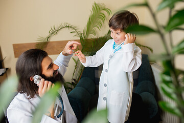 Image showing Paediatrician doctor examining a child while wearing face mask in comfortabe medical office