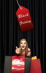 Image showing Beautiful woman inviting for shopping in black friday, sales concept. Vertical flyer, dark background