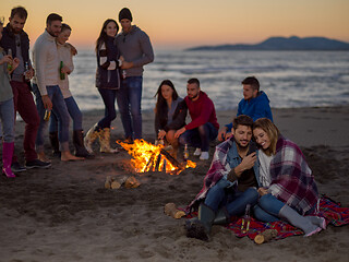 Image showing Couple enjoying bonfire with friends on beach