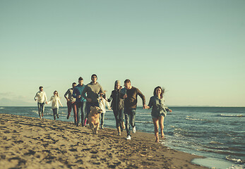 Image showing Group of friends running on beach during autumn day