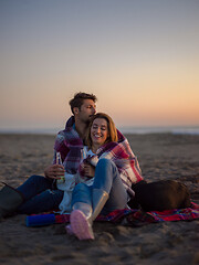 Image showing Loving Young Couple Sitting On The Beach beside Campfire drinkin