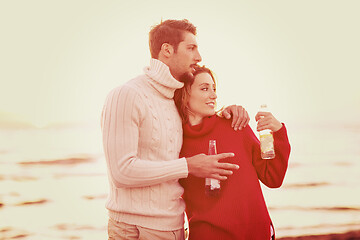 Image showing Couple hugging and drinking beer together at the beach