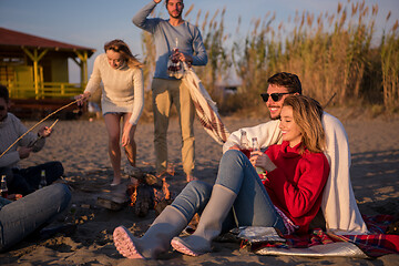 Image showing Couple enjoying with friends at sunset on the beach