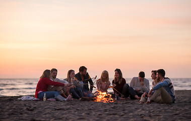 Image showing Group Of Young Friends Sitting By The Fire at beach