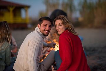 Image showing Couple enjoying with friends at sunset on the beach