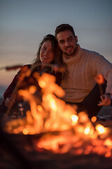 Image showing Group Of Young Friends Sitting By The Fire at beach