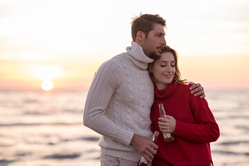 Image showing Couple hugging and drinking beer together at the beach