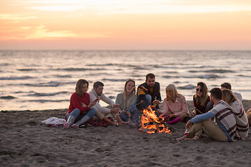 Image showing Group Of Young Friends Sitting By The Fire at beach