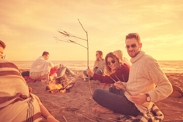 Image showing Couple enjoying with friends at sunset on the beach