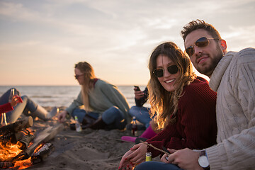 Image showing Couple enjoying with friends at sunset on the beach