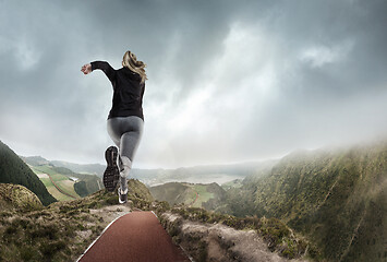 Image showing Young woman running and jumping near mountains and lake