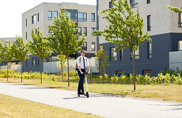 Image showing businessman with backpack riding electric scooter