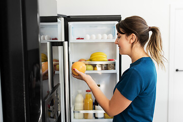 Image showing happy woman taking food from fridge at home