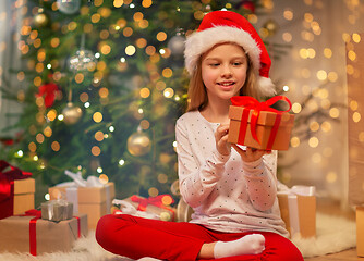 Image showing smiling girl in santa hat with christmas gift