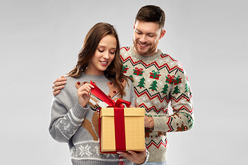 Image showing happy couple in christmas sweaters with gift box