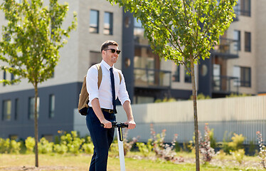 Image showing businessman with backpack riding electric scooter