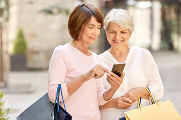 Image showing old women with shopping bags and cellphone in city