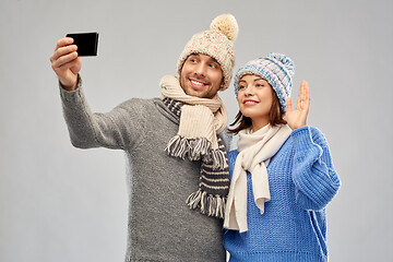 Image showing couple in winter hats taking selfie by smartphone