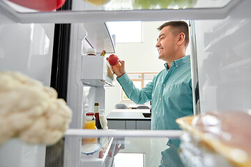 Image showing man taking apple from fridge at home kitchen