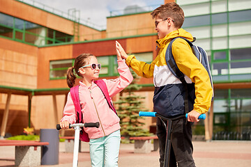 Image showing happy school children with backpacks and scooters