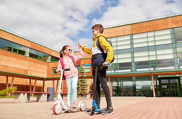 Image showing happy school children with backpacks and scooters