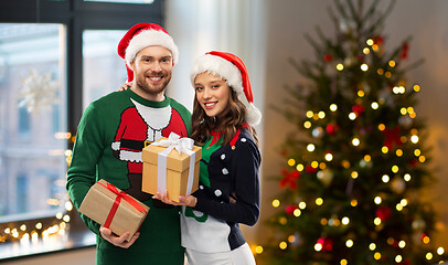 Image showing happy couple in sweaters with christmas gifts