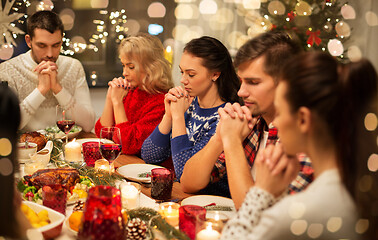 Image showing friends having home christmas dinner and praying