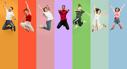 Image showing Freedom in moving. Pretty young women and men jumping against colorful background