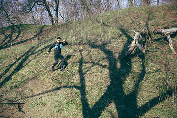 Image showing Man running in a park or forest against trees background.