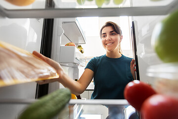 Image showing happy woman taking food from fridge at home