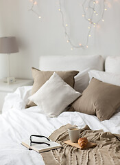 Image showing coffee, croissant, blanket and book on bed at home