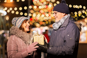 Image showing happy senior couple with gift at christmas market