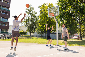 Image showing group of male friends playing street basketball