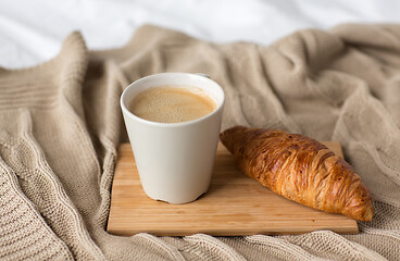 Image showing cup of coffee and croissant on bed or blanket