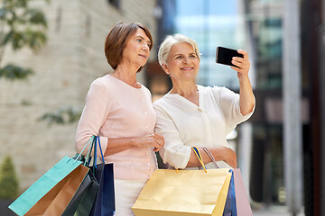 Image showing old women with shopping bags taking selfie in city