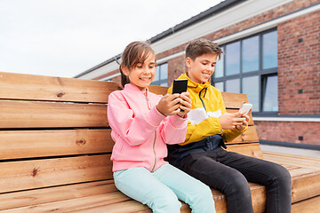 Image showing children with smartphones sitting on street bench