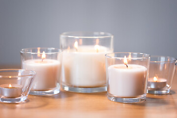 Image showing burning white fragrance candles on wooden table