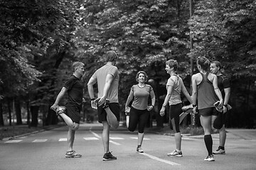 Image showing runners team warming up and stretching before morning training