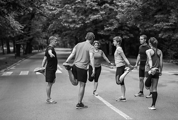 Image showing runners team warming up and stretching before morning training