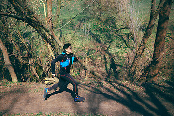 Image showing Man running in a park or forest against trees background.