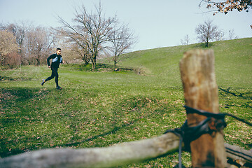 Image showing Man running in a park or forest against trees background.