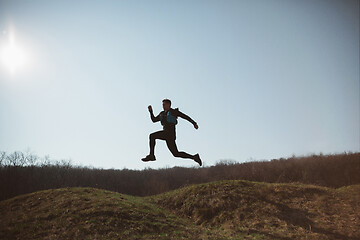 Image showing Man running in a park or forest against trees background.