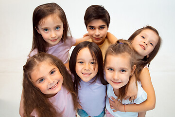 Image showing The portrait of cute little boy and girls in stylish clothes looking at camera at studio