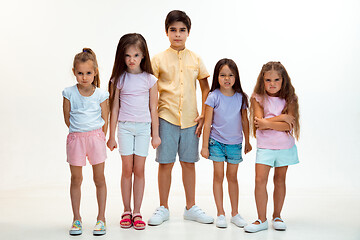 Image showing The portrait of cute little boys and girls in stylish clothes looking at camera at studio